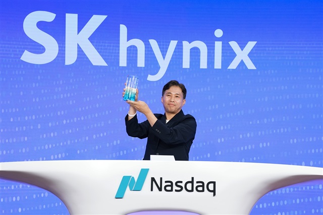 Representante de SK hynix sosteniendo un trofeo en el podio de Nasdaq con un fondo azul corporativo